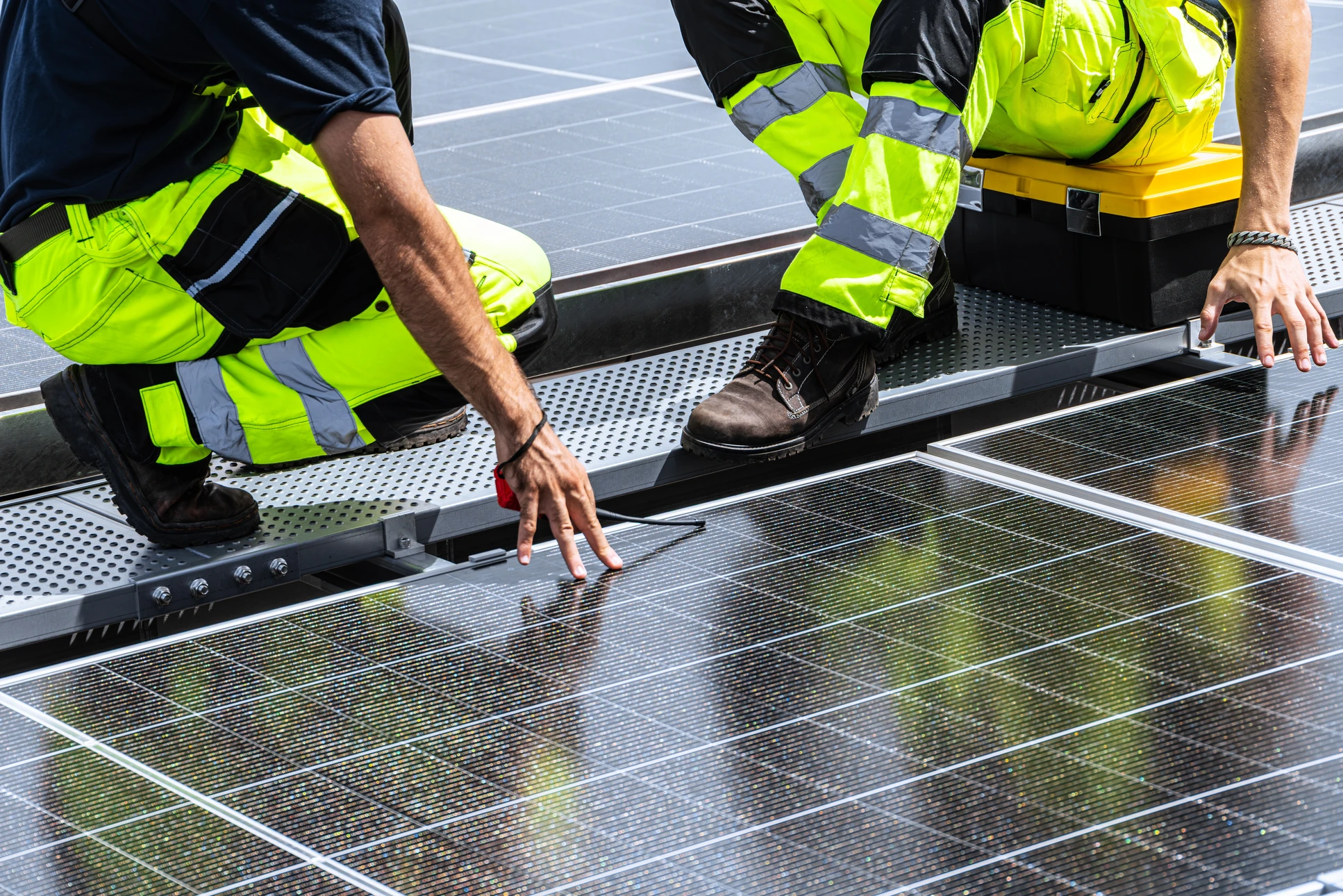 Deux professionnels sur un toit analysent des données sur tablette numérique près d'une installation de panneaux solaires photovoltaïques