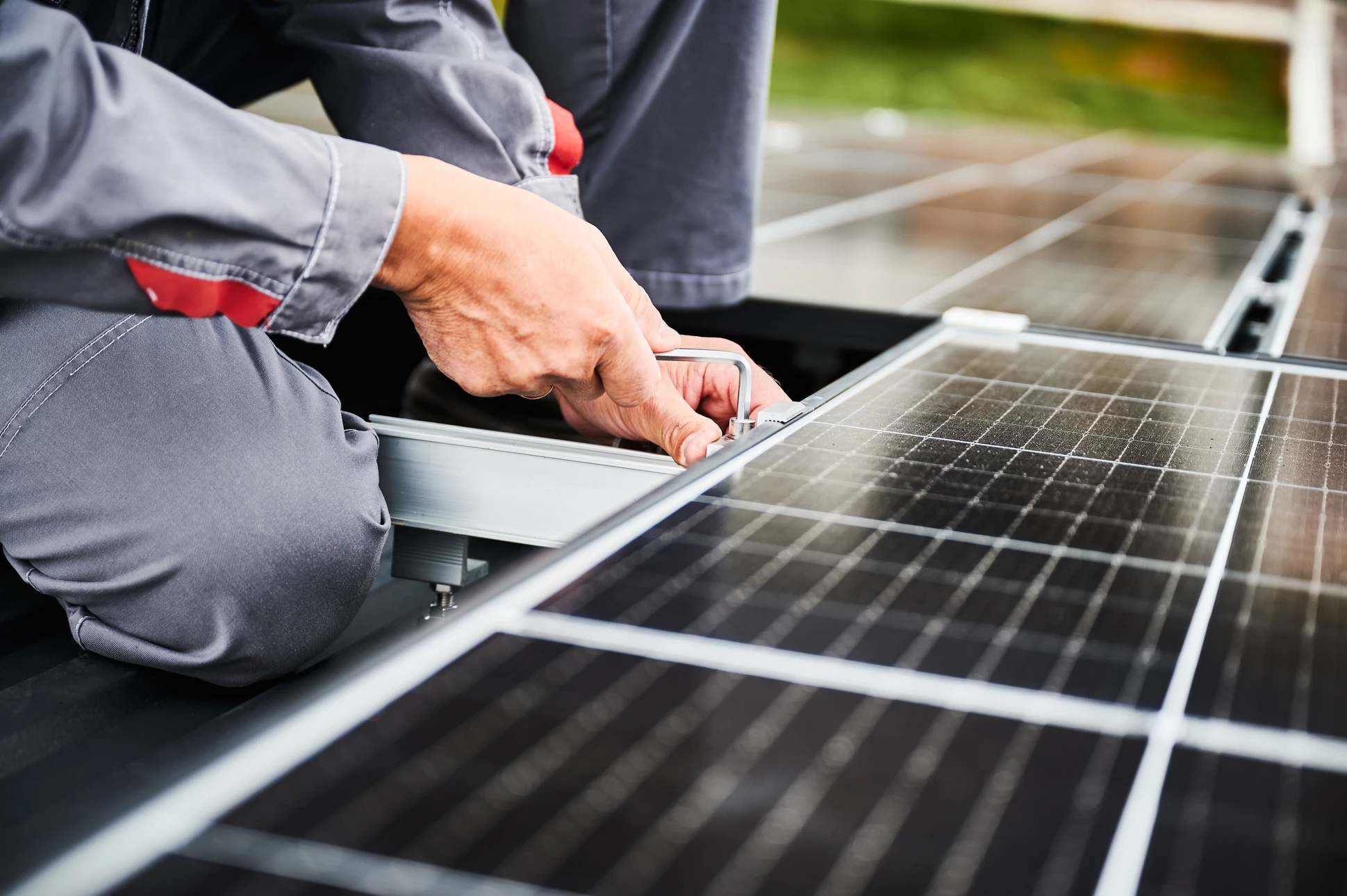 Ouvrier installateur en combinaison et casque de protection travaillant sur toiture, manipulant des panneaux photovoltaïques solaires